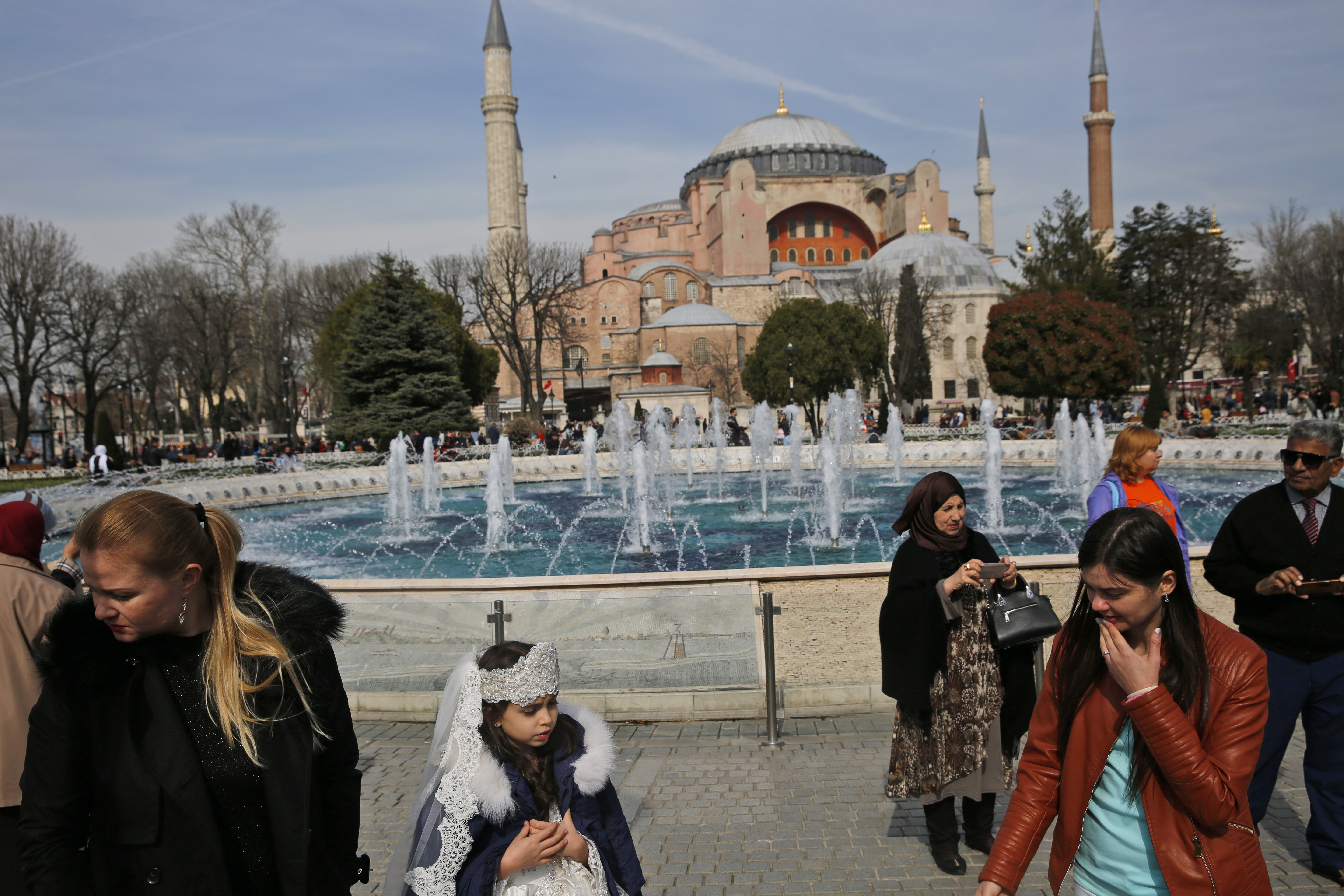 FILE - In this Friday, March 24, 2017 file photo, people walk backdropped by the Byzantine-era Hagia Sophia, one of Istanbul's main tourist attractions, in the historic Sultanahmet district of Istanbul. The 6th-century building is now at the center of a heated debate between conservative groups who want it to be reconverted into a mosque and those who believe the World Heritage site should remain a museum. (AP Photo/Lefteris Pitarakis, File)