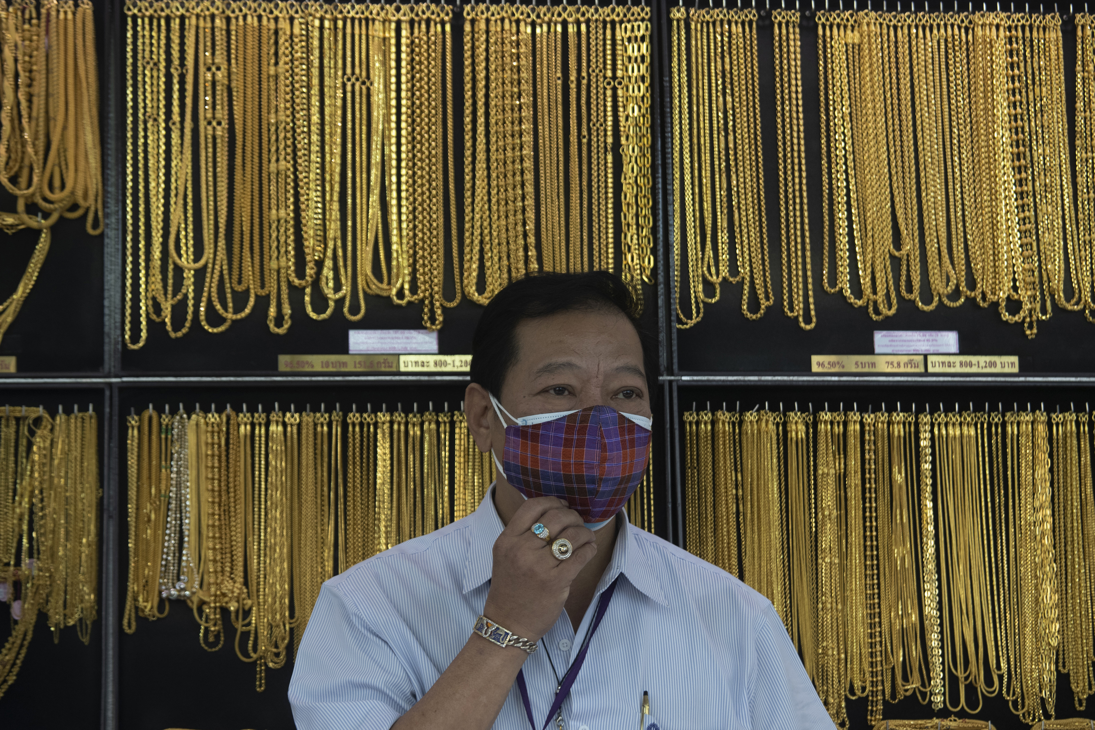 FILE - In this April 16, 2020, file photo, a Thai shopkeeper adjusts his face mask at a gold shop in Bangkok, Thailand. The price of gold surged more than $30 on Monday, July 27, 2020 to over $1,926 per ounce as investors step up buying of the precious metal often sought in times of uncertainty. Gold was trading at $1,926.20 by early afternoon in Asia, up 1.5%, after surging over the weekend. Photo: AP