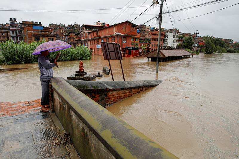 A man stands on a bridge as a river overflows due to incessant rainfall in Bhaktapur, on Monday, July 20, 2020. Photo: Reuters