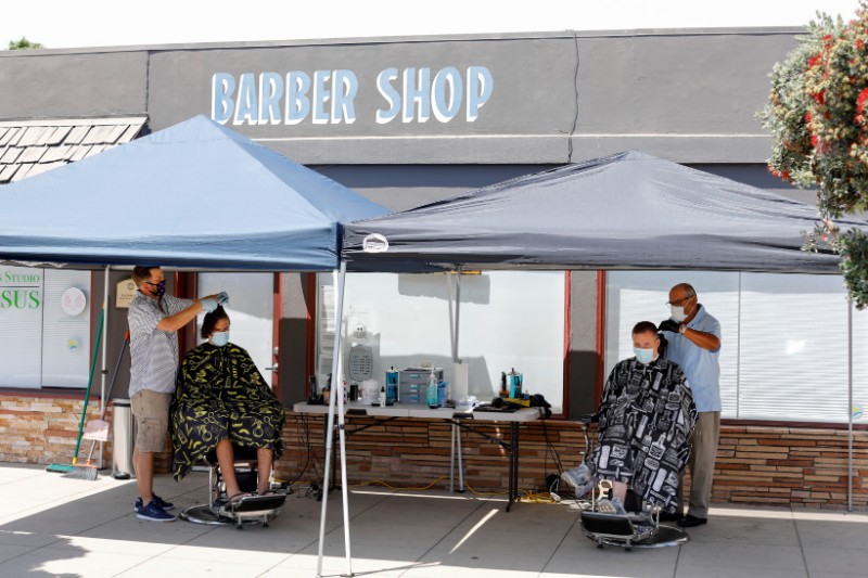 Barbers cut hair on the sidewalk in front of their shop during the outbreak of the coronavirus disease in California  in Solana Beach, California, US, on July 21, 2020. Photo: Reuters