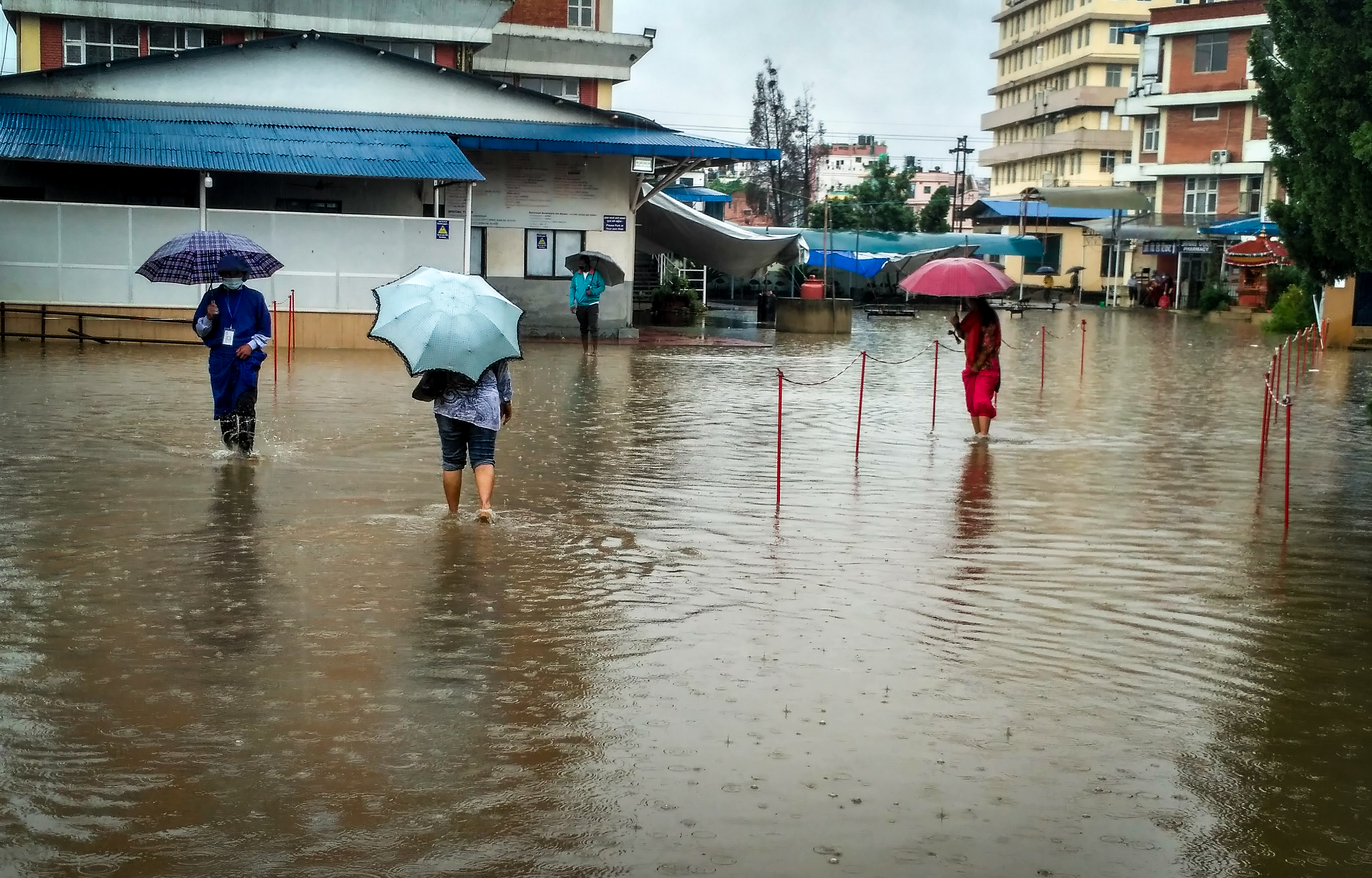 People wade through a flooded area in the premises of Kist Hospital, in Lalitpur, on Tuesday, July 21, 2020. Photo: Naresh Shrestha/THT