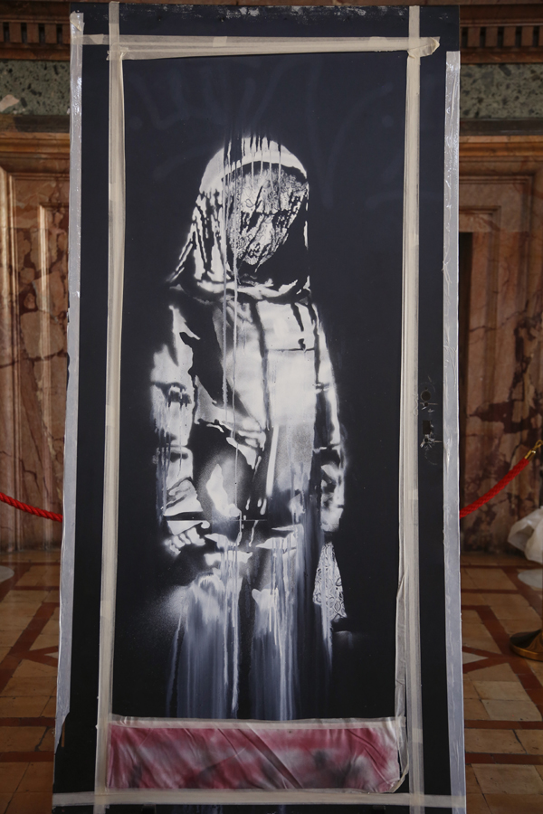 A recovered stolen artwork by British artist Banksy, depicting a young female figure with a mournful expression, that was painted as a tribute to the victims of the 2015 terror attacks at the Bataclan music hall in Paris, is shown during a ceremony at the French Embassy in Rome, Tuesday, July 14, 2020. Photo: AP