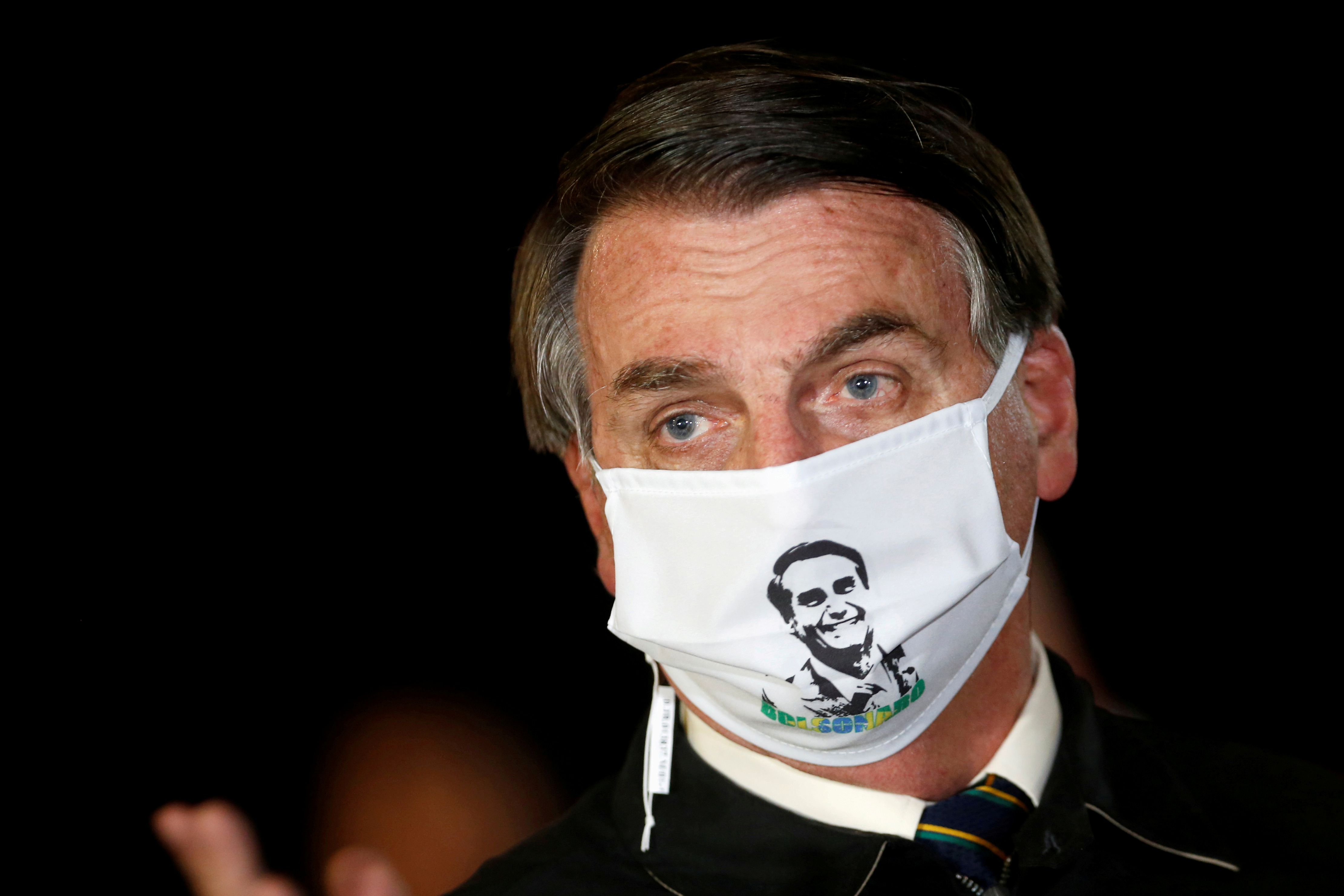 FILE PHOTO: Brazil's President Jair Bolsonaro speaks with journalists while wearing a protective face mask as he arrives at Alvorada Palace, amid the coronavirus disease (COVID-19) outbreak, in Brasilia, Brazil, May 22, 2020. Photo: Reuters