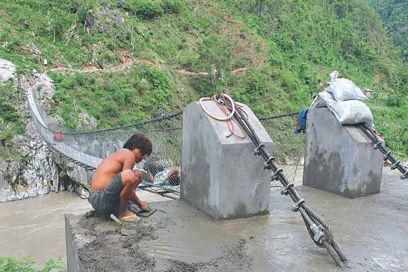 A man working at the entrance of a suspension bridge in Benighat Rorang, Dhading, on Sunday. Photo: THT