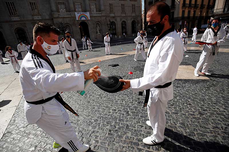 A man wearing a protective face mask uses a disinfection spray as people perform taekwondo during a protest against the closure of gyms, amid the coronavirus disease (COVID-19) outbreak, at Sant Jaume square in Barcelona, Spain, on July 27, 2020.Photo: Reuters