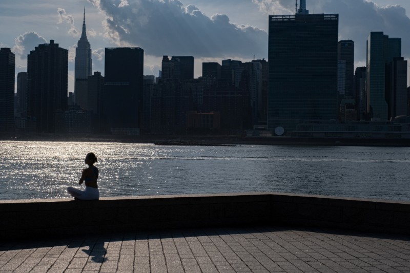 A woman meditates while enjoying a warm and humid day at Gantry Plaza State Park following the outbreak of the coronavirus disease (COVID-19), in Long Island City, New York, U.S., July 25, 2020. Photo: Reuters