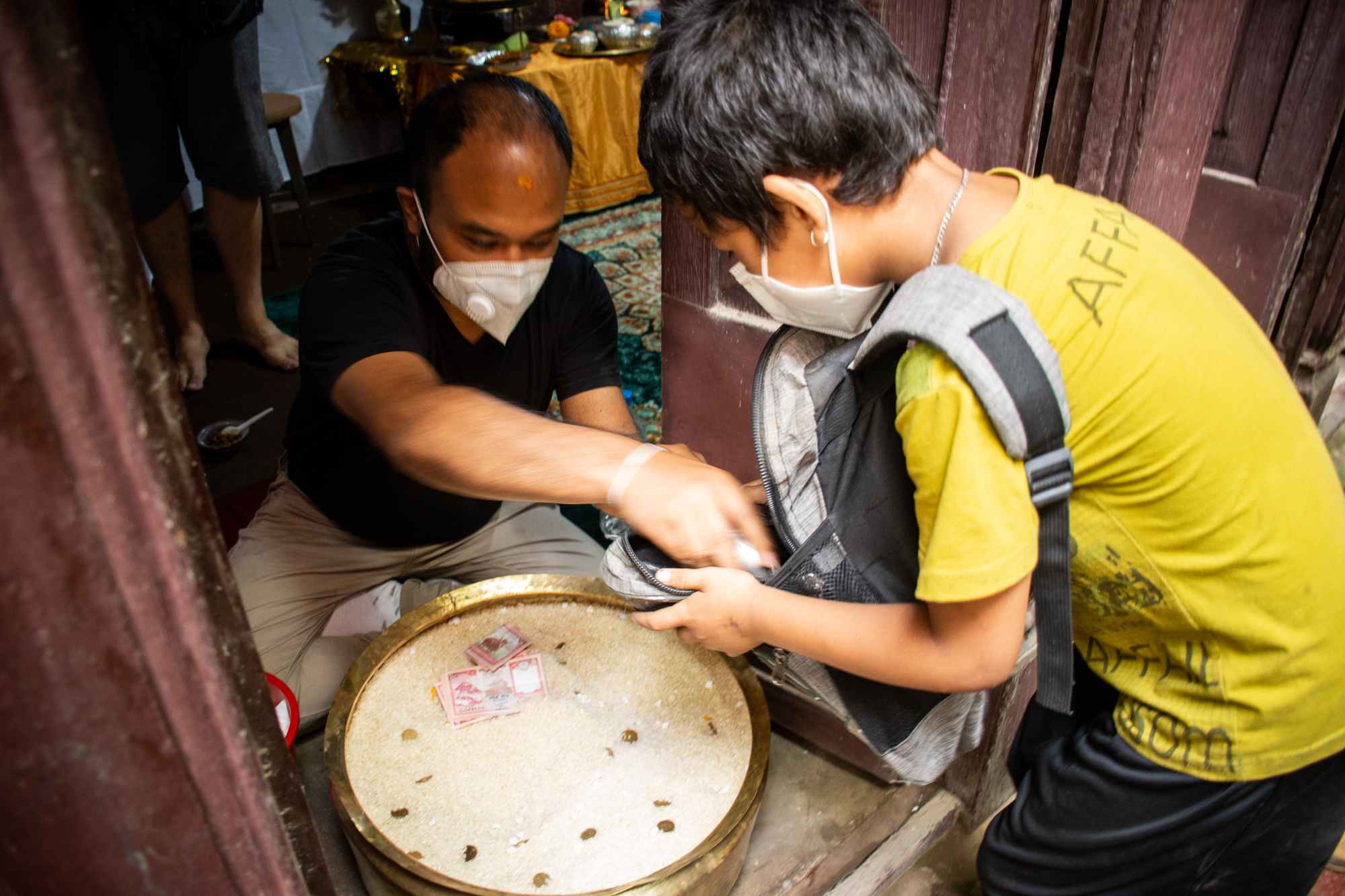Buddhist devotees receive offerings during the Pancha Daan festival in Lalitpur, on Tuesday, July 28, 2020. Pancha Daan means giving five different items including rice grains, unhusked rice grains, salt, pulses, and money that are needed for one’s daily living. Photo: Naresh Shrestha/THT