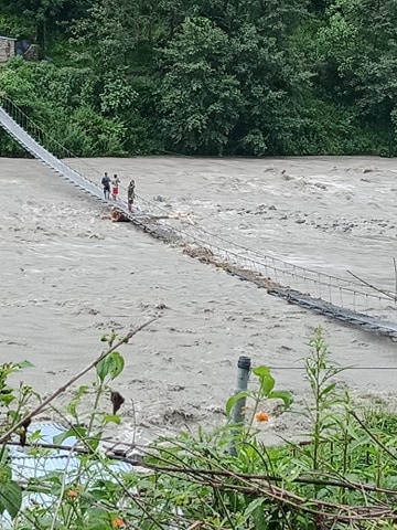 Taprisera suspension bridge is seen partially submerged in Budhiganga river, Bajura district. Photo: Prakash Singh/THT