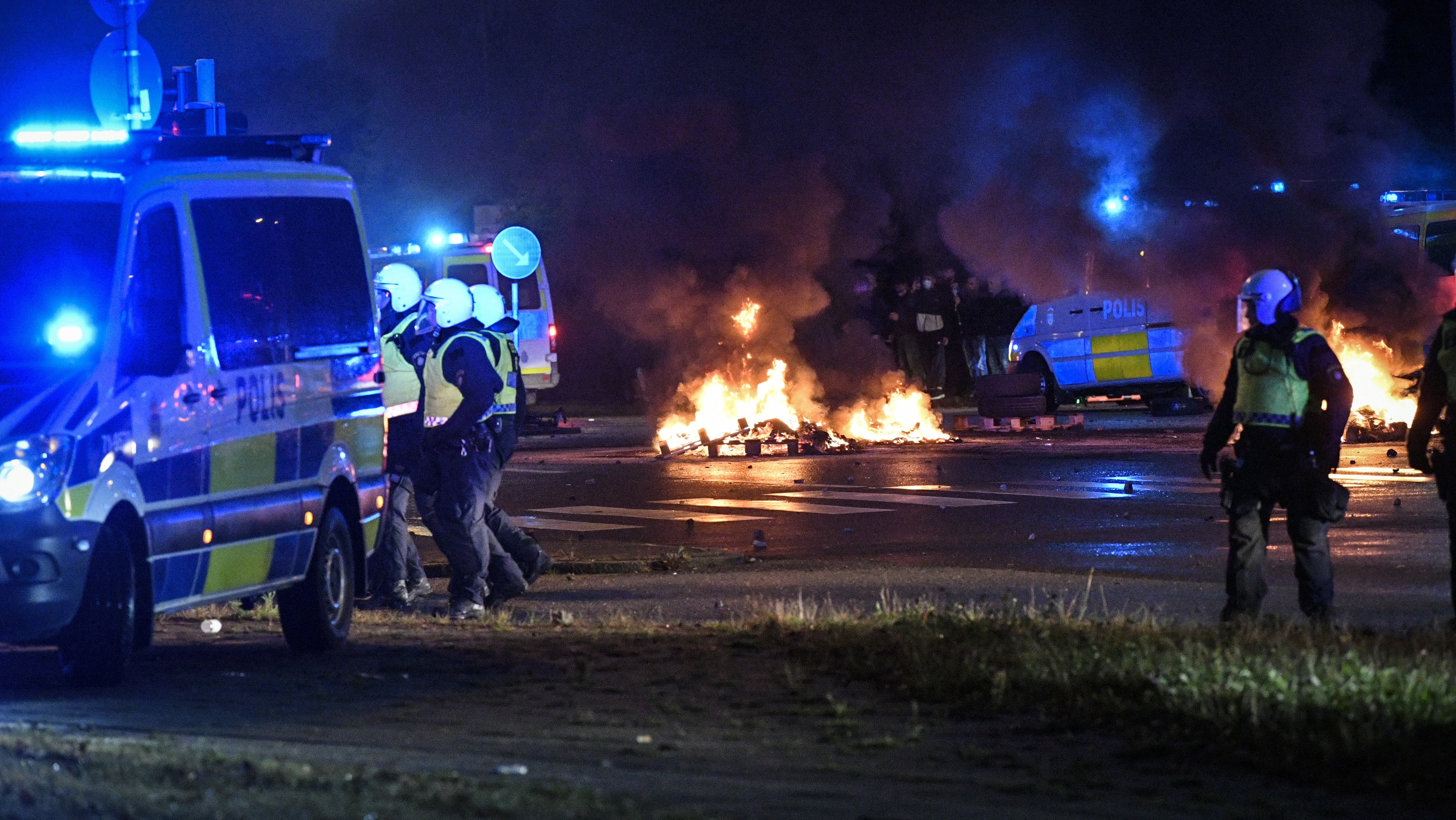 Riot police on the scene as smoke billows from burning tires and fireworks, as a few hundred protesters riot in the Rosengard neighbourhood of Malmo, Sweden, Friday, Aug. 28, 2020. Far-right activists burned a Quran in the southern Swedish city of Malmo, sparking riots and unrest after more than 300 people gathered to protest, police said Saturday. Rioters set fires and threw objects at police and rescue services Friday night, slightly injuring several police officers and leading to the detention of about 15 people. (TT News Agency via AP)