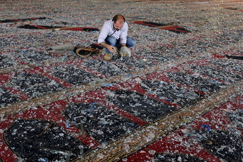 A man removes broken glass scattered on the carpet of a mosque damaged in Tuesday's blast in Beirut, Lebanon August 5, 2020. Photo: Reuters