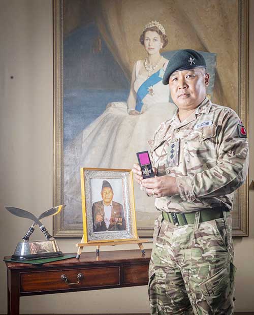 Captain Buddhi Gurung, a member of Brigade of Gurkhas, holding his grandfatheru2019s Victoria Cross medal near a framed photo of Rifleman Bhanbhagta Gurung. Photo courtesy: British Army