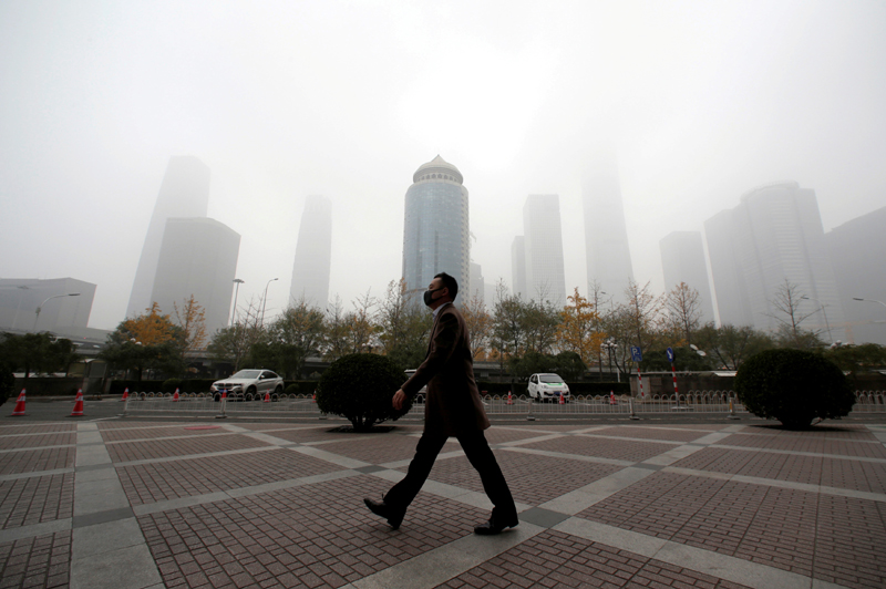 FILE PHOTO: A man wearing a mask walks in the central business district on a polluted day after a yellow alert was issued for smog, in Beijing, China November 14, 2018.  Photo: Reuters