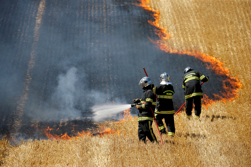 French firefighters extinguish a fire in a burning field of wheat during harvest season in Aubencheul-au-Bac, France, July 21, 2020. Picture taken July 21, 2020. Photo: Reuters