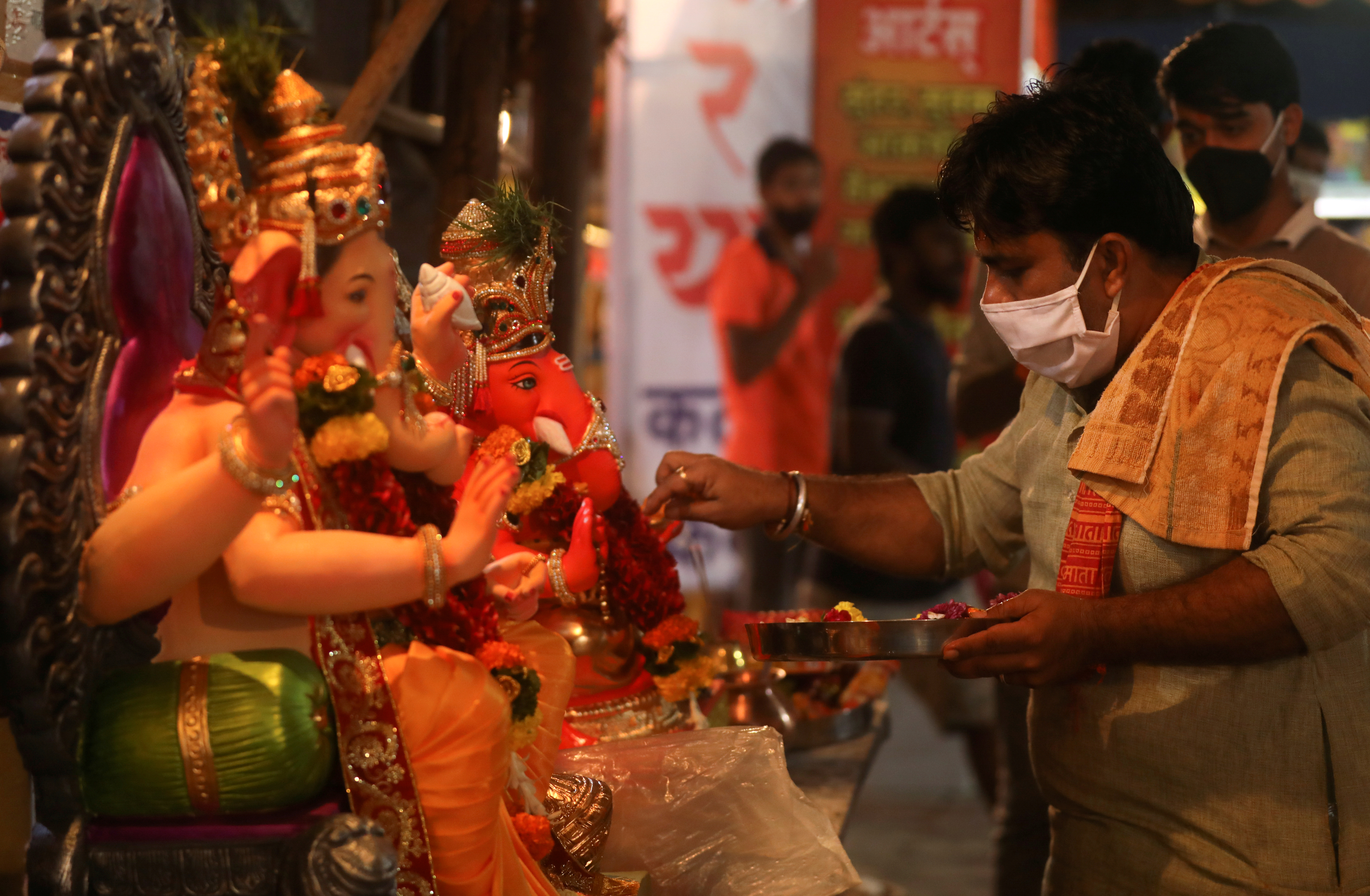 A Hindu priest wearing a protective face mask conducts a puja in front of idols of Hindu God Ganesh,  the deity of prosperity, before they can be taken home ahead of the Ganesh Chaturthi festival in Mumbai, India August 21, 2020. Photo: Reuters