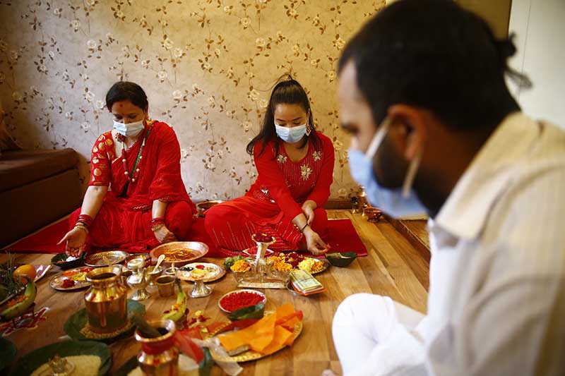 Women along with a priest perform prayer rituals at their home during Teej festival in Lalitpur, on Friday, August 21, 2020. The government has issued a week-long prohibitory order in the valley and restricted public gatherings to prevent the spread of novel coronavirus.  Devotees and revellers are confined to their homes as the festival coincides with the second day of the prohibitory order. Photo: Skanda Gautam/THT