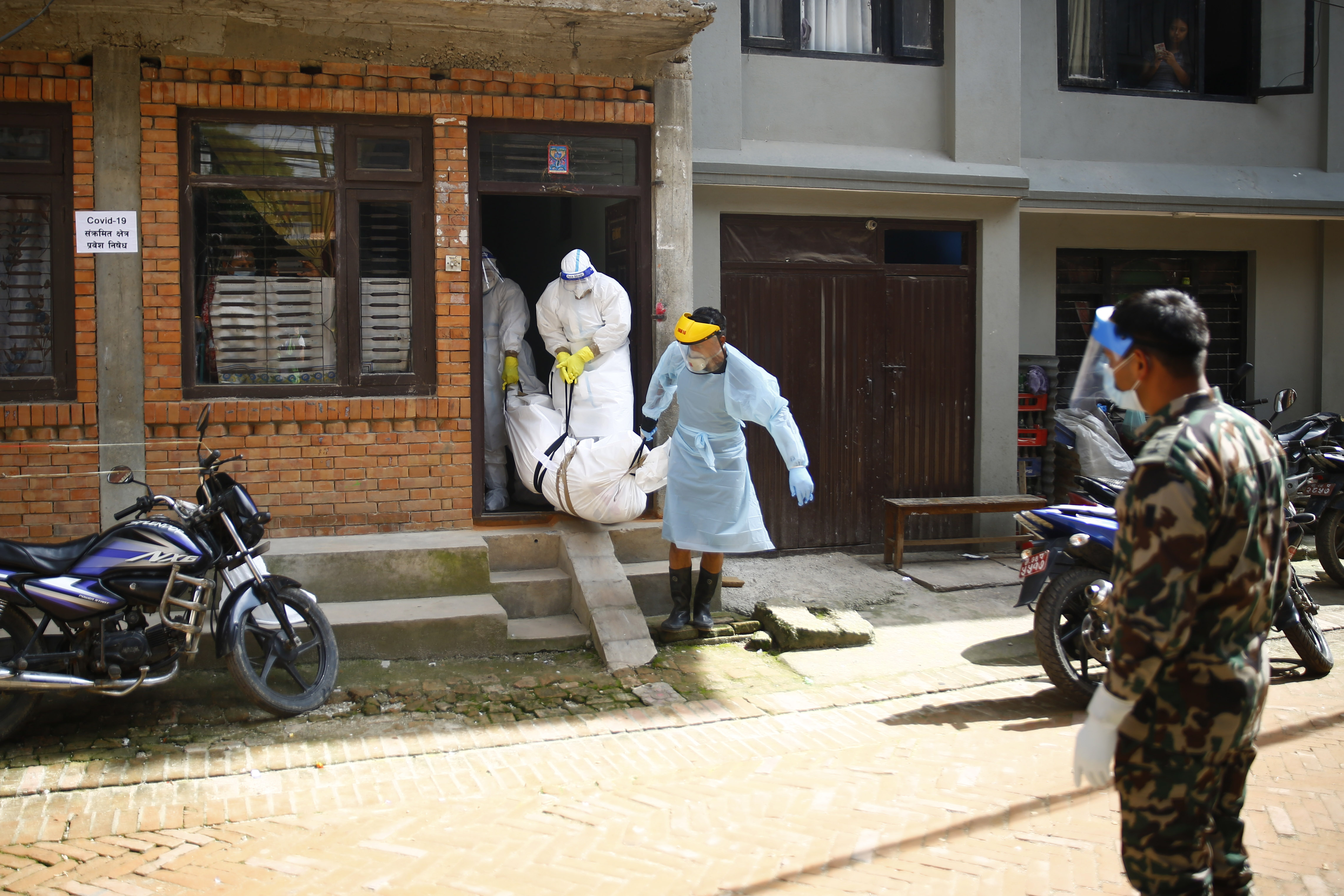 Army personnel along with RNA-16 volunteers bring down COVID-19 victim's body from a house where he died while remaining in isolation, before taking for funeral, in Bhaktapur, on Sunday, August 30, 2020. Photo: Skanda Gautam/THT 