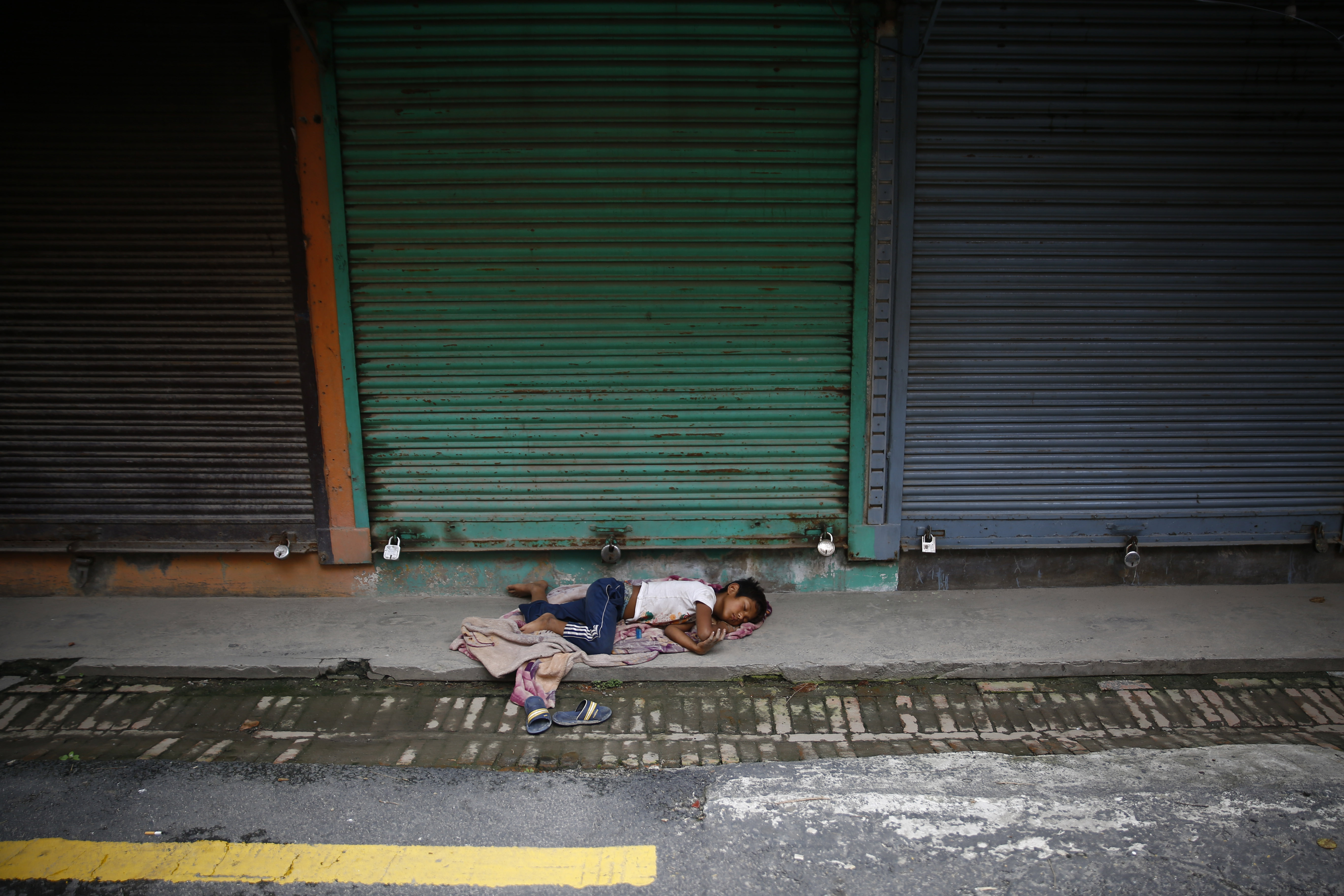 A street child sleeps in front of shuttered shops at Thamel, a tourist hub, after the government re-imposed a lockdown amid concerns over the spread of coronavirus disease in Kathmandu, on Friday, August 28, 2020. Photo: Skanda Gautam/THT