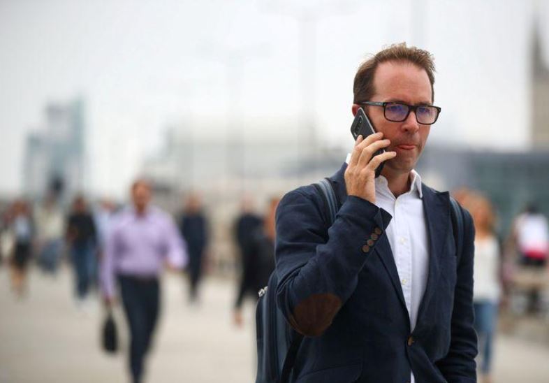 FILE PHOTO: A man talks on his mobile phone as commuters walk across the London Bridge during the morning rush hour, amid an outbreak of the coronavirus disease (COVID-19), in London, Britain September 21, 2020. Photo: Reuters