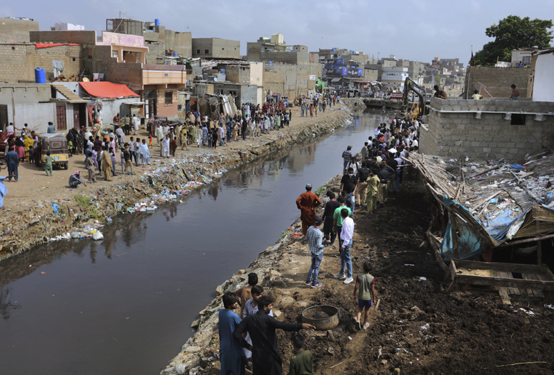 Residents watch the arrival of local authorities to demolish illegal construction alongside a drainage canal which saw flooding last week due to heavy monsoon rains, in Karachi, Pakistan, Wednesday, Sept. 2, 2020. Photo: AP