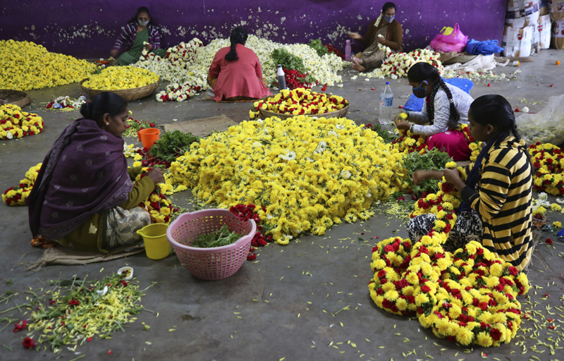 Flower vendors, some wearing face masks as a precaution against coronavirus, prepare garlands at a wholesale market in Bengaluru, India, Thursday, Sept. 24, 2020. Photo: AP