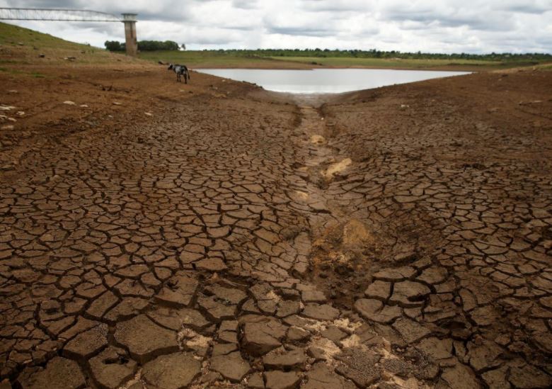 FILE PHOTO: Caked mud is seen before a small patch of water as the region deals with a prolonged drought at a dam near Bulawayo, Zimbabwe, January 18, 2020. Picture taken January 18, 2020.  Photo: Reuters