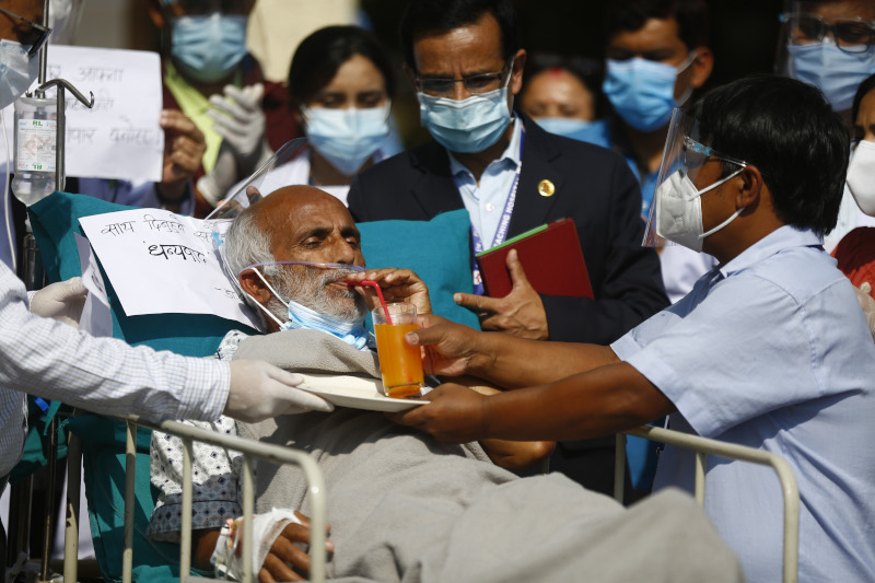 Dr Govinda KC drinks juice from the hands of Bikash Nepali, a COVID-19 recovered sanitation staff of Teaching Hospital while ending his fast unto death hunger strike on the 28th day, at Teaching Hospital in Kathmandu, Nepal on Sunday, October 11, 2020. Photo: Skanda Gautam/ THT