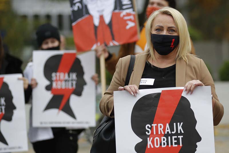 Women's rights activists with posters of the Women's Strike action protest against recent tightening of Poland's restrictive abortion law in front of the parliament building as inside, guards had to be used to shield right-wing ruling party leader Jaroslaw Kaczynski from angry opposition lawmakers, in Warsaw, Poland, on Tuesday, October 27, 2020. Photo: AP