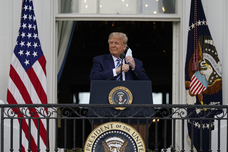 President Donald Trump removes his face mask to speak from the Blue Room Balcony of the White House to a crowd of supporters, Saturday, Oct. 10, 2020, in Washington. Photo: AP