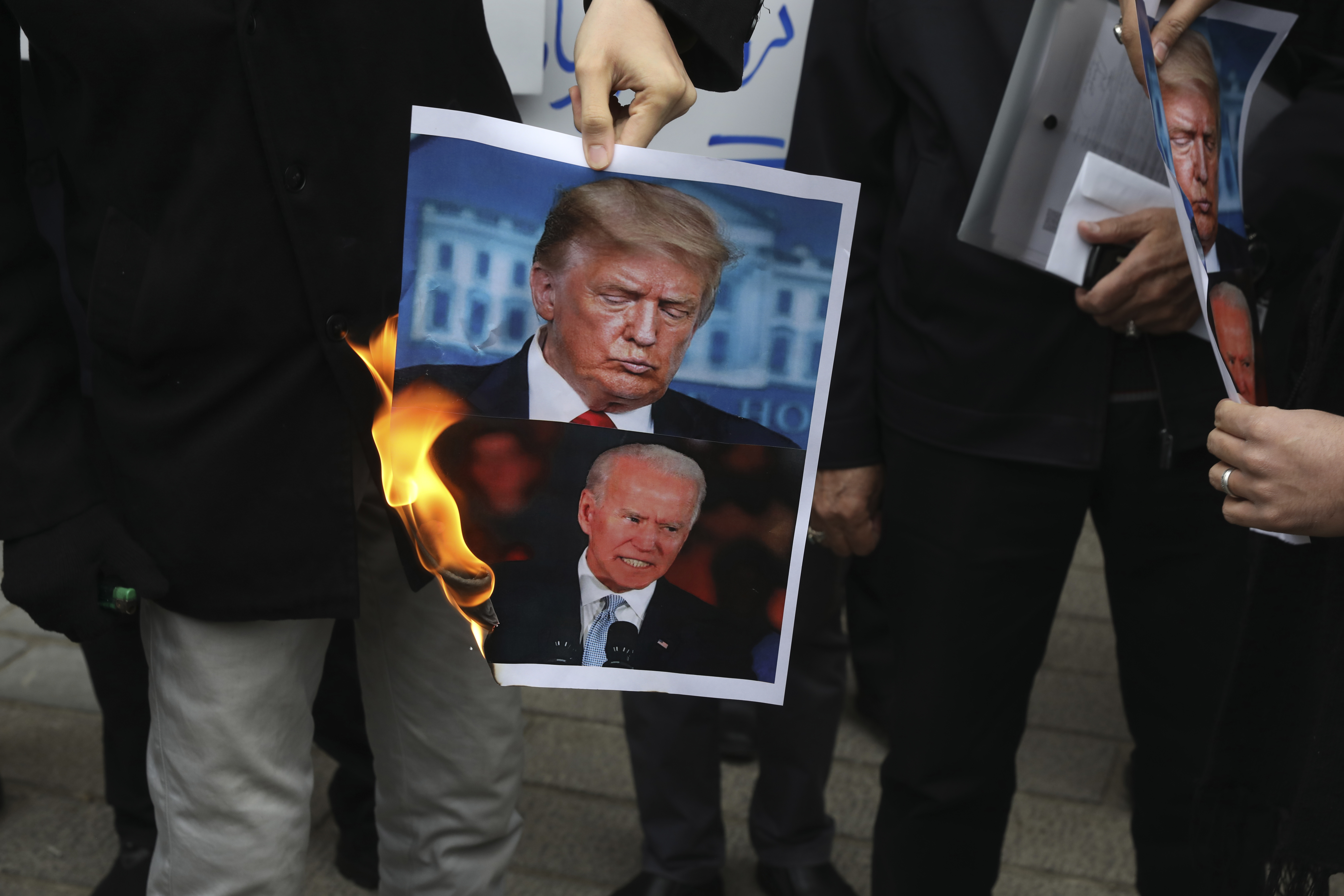 A group of protesters burn pictures of the U.S. President Donald Trump, top, and the President-elect Joe Biden in a gathering in front of Iranian Foreign Ministry on Saturday, Nov. 28, 2020, a day after the killing of Mohsen Fakhrizadeh an Iranian scientist linked to the country's nuclear program by unknown assailants near Tehran. Photo: AP