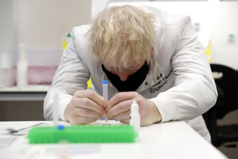 Britain's Prime Minister Boris Johnson, wearing a mask because of the coronavirus,  has a close look at a sample at the Lateral Flow Testing Laboratory during a visit to the Public Health England site at Porton Down science park near Salisbury, southern England, on Friday Nov. 27, 2020. Photo: Adrian Dennis/Pool via AP