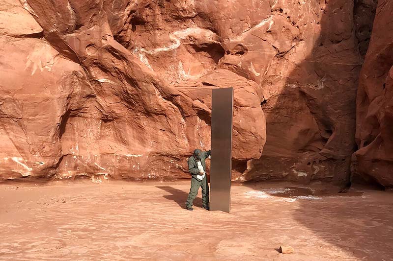 This image shows a Utah state worker inspecting a metal monolith that was found installed in the ground in a remote area of red rock in Utah, on November 18, 2020. Photo: Utah Department of Public Safety via AP