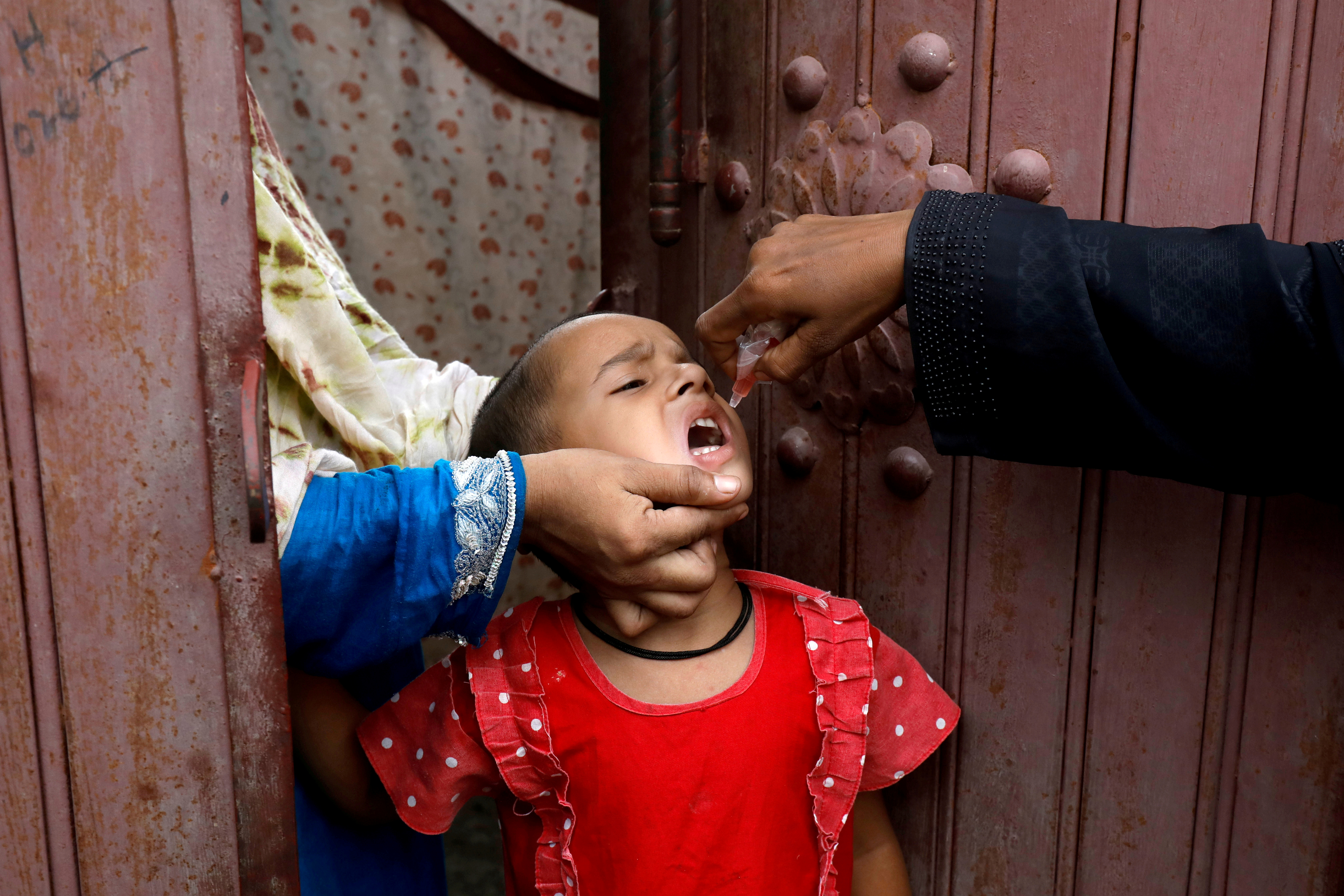 FILE PHOTO: A girl receives polio vaccine drops, during an anti-polio campaign, in a low-income neighborhood as the spread of the coronavirus disease (COVID-19) continues, in Karachi, Pakistan July 20, 2020. REUTERS/Akhtar Soomro/File Photo