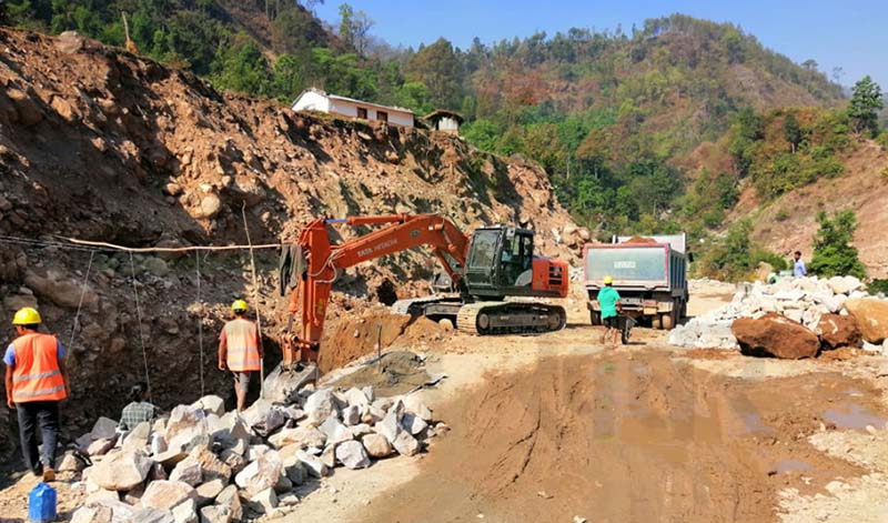 Workers are seen at the site while an excavator is being used to dig the section of Sahajpur-Bogatan road. The road that links Kailali's Sahajpur to Doti's Bogatan began in 1987 but even today, the road section is yet to be completed. Photo: Tekendra Deuba/THT