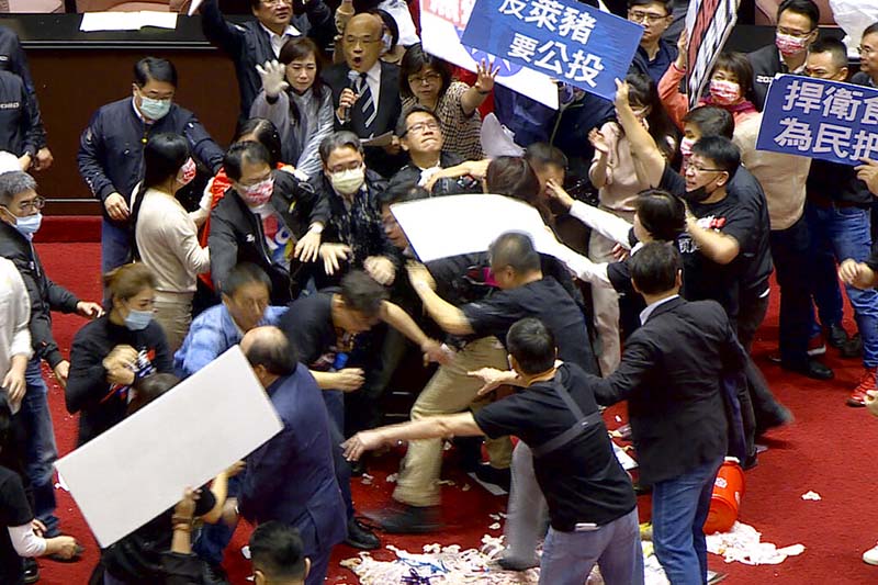In this image made from video, lawmakers fight during a parliament session in Taipei, Taiwan, on Friday, November 27, 2020. Taiwan's lawmakers got into a fist fight and threw pig guts at each other on Friday over a soon-to-be enacted policy that would allow imports of US pork and beef. The banner at center top reads: u201cProtest against ractopamine pork, We want a referendum.u201d Image: FTV via AP