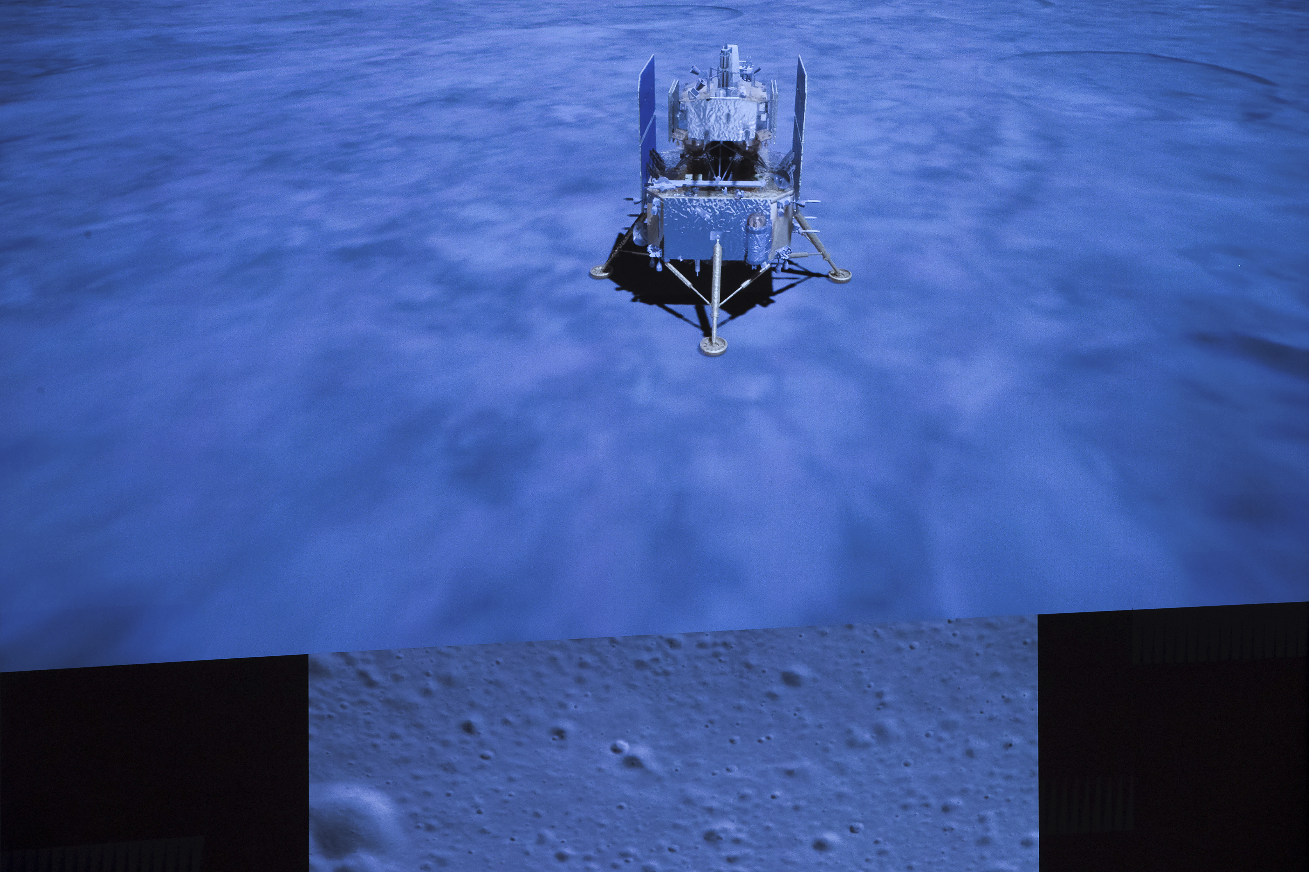 In this photo released by Xinhua News Agency, a screen shows the landed Chang'e-5 spacecraft and a moon surface picture, below, taken by camera aboard Chang'e-5 spacecraft during its landing process, at Beijing Aerospace Control Center (BACC) in Beijing on Tuesday, Dec. 1, 2020. A Chinese spacecraft landed on the moon Tuesday to bring back lunar rocks to Earth for the first time since the 1970s, the government announced. Photo: AP