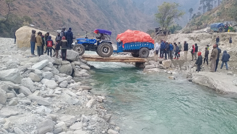 A tractor is seen crossing the Budhiganga river through a newly constructed wooden bridge in Badimalika Municipality of Bajura district, on Tuesday, December 29, 2020. Photo: Prakash Singh/THT