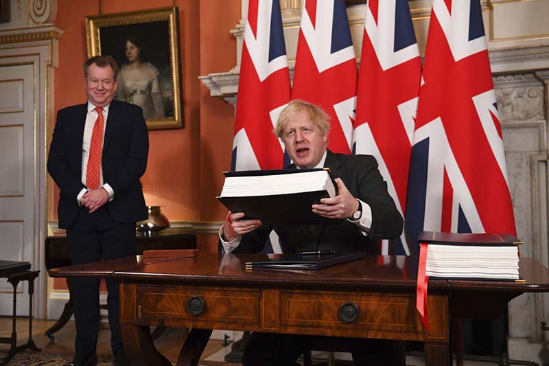 UK chief trade negotiator David Frost looks on as Britain's Prime Minister Boris Johnson signs the EU-UK Trade and Cooperation Agreement at 10 Downing Street, London, on Wednesday, December 30, 2020. Photo: Leon Neal/Pool via AP