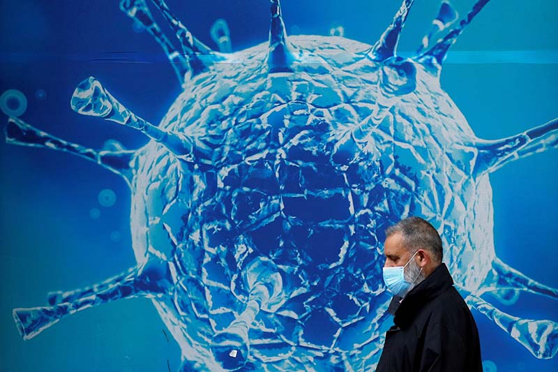 FILE -  A man wearing a protective face mask walks past an illustration of a virus outside a regional science centre in Oldham, Britain, on August 3, 2020.Photo: Reuters