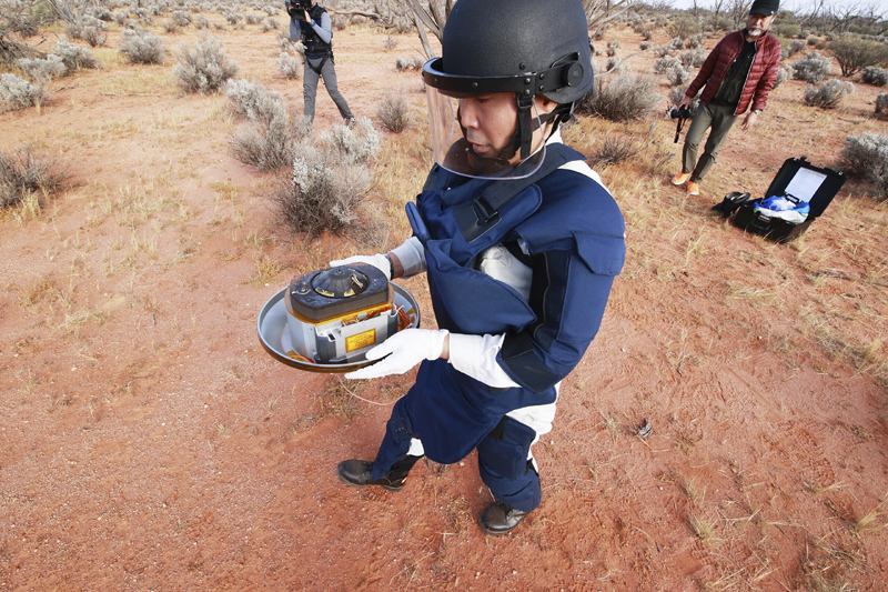 In this photo provided by the Japan Aerospace Exploration Agency (JAXA), a member of JAXA retrieves a capsule dropped by Hayabusa2 in Woomera, southern Australia, Sunday, Dec. 6, 2020. A Japanese capsule carrying the first samples of asteroid subsurface shot across the night atmosphere early Sunday before successfully landing in the remote Australian Outback, completing a mission to provide clues to the origin of the solar system and life on Earth. Photo: JAXA via AP