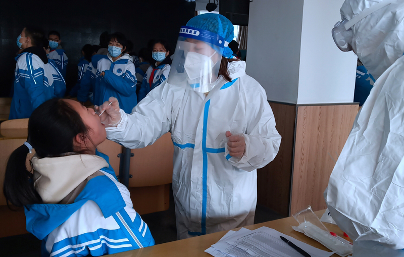 A medical worker in a protective suit collects a swab sample from a middle school student during a mass nucleic acid testing following a recent coronavirus disease (COVID-19) outbreak in Xingtai, Hebei province, China January 6, 2021. Photo: China Daily via Reuters